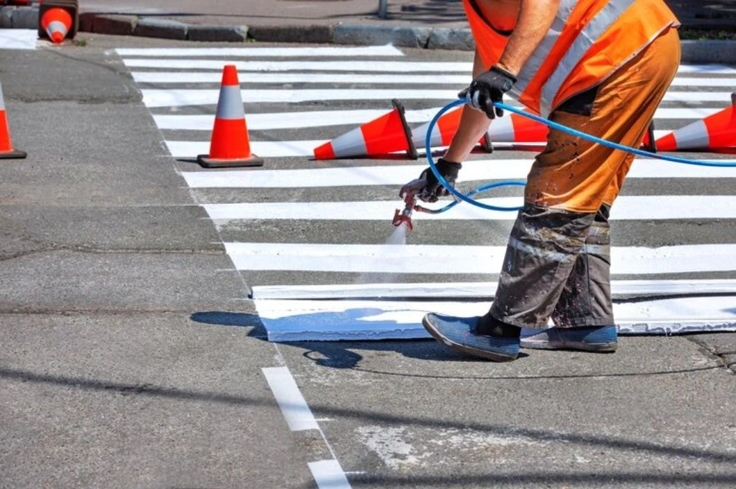 Construction worker applying road paint markings